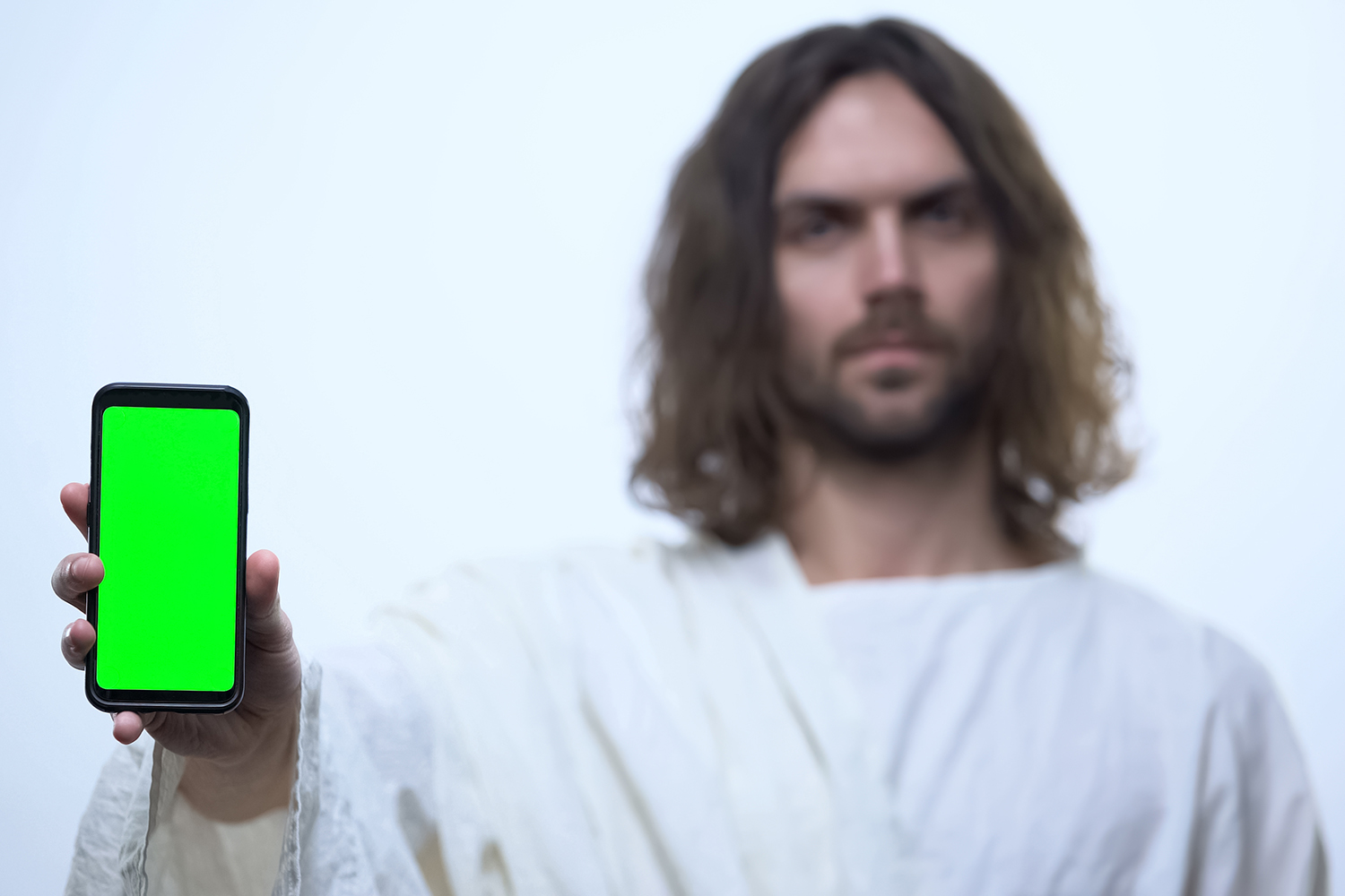 An image of a man dressed as Jesus holding a cellphone.