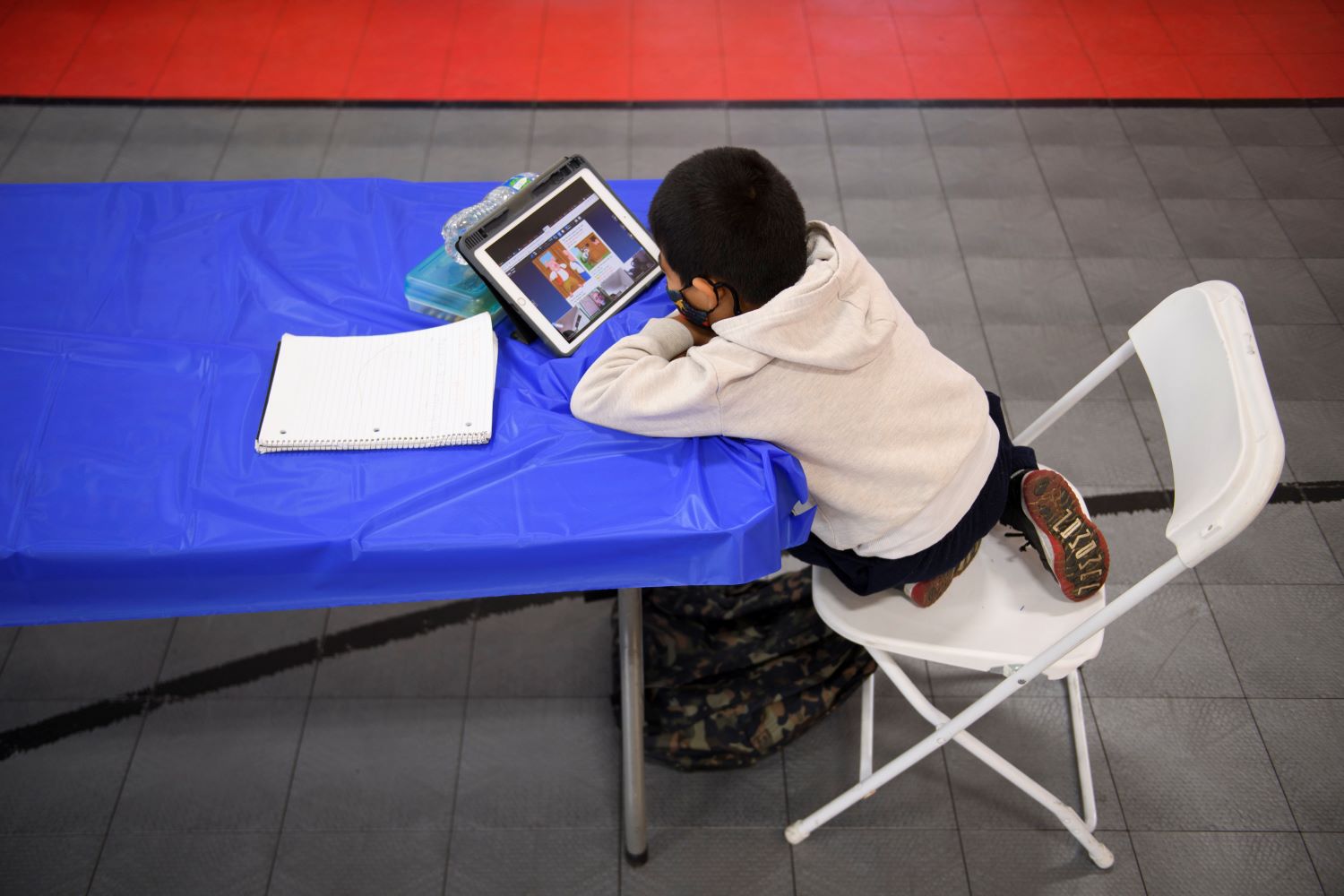 An overhead shot of a student sitting at a table staring at a laptop screen.