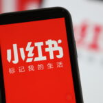 A mobile phone shows the app interface of Xiaohongshu, also known as RedNote