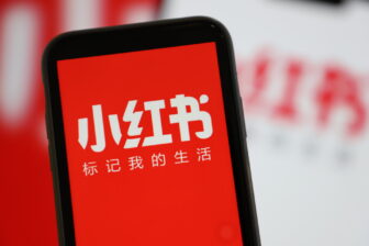 A mobile phone shows the app interface of Xiaohongshu, also known as RedNote