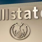 The side of a tan building showing Allstate's name and logo, a circle around two cupped hands.