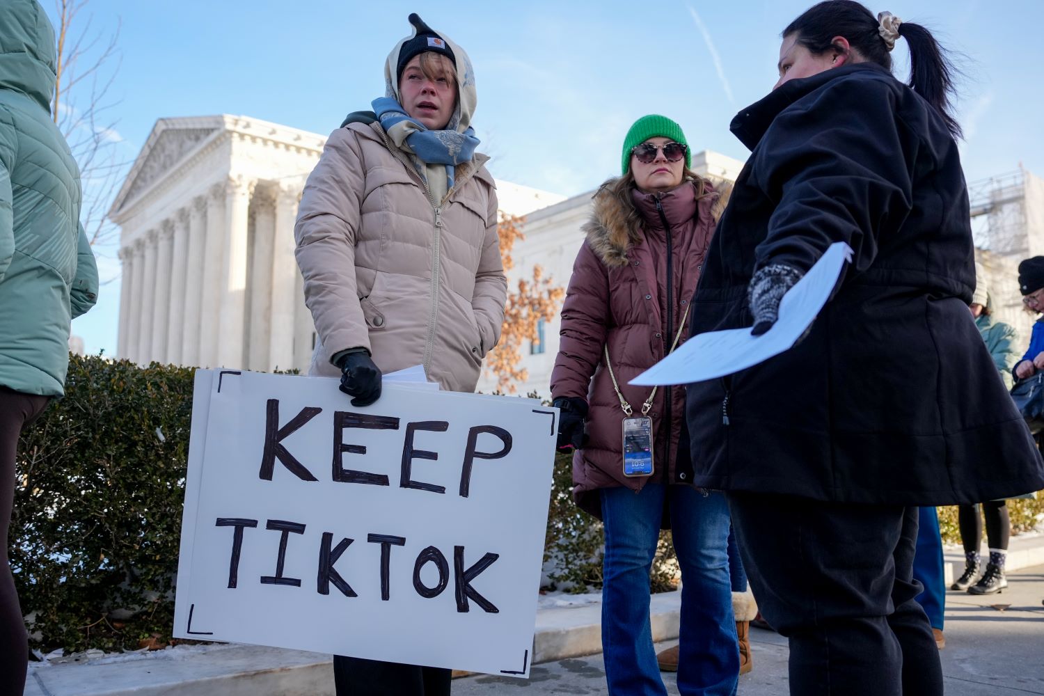 Demonstrators in coats outside the Supreme Court building, one holding a white sign with black lettring reading "Keep TikTok."