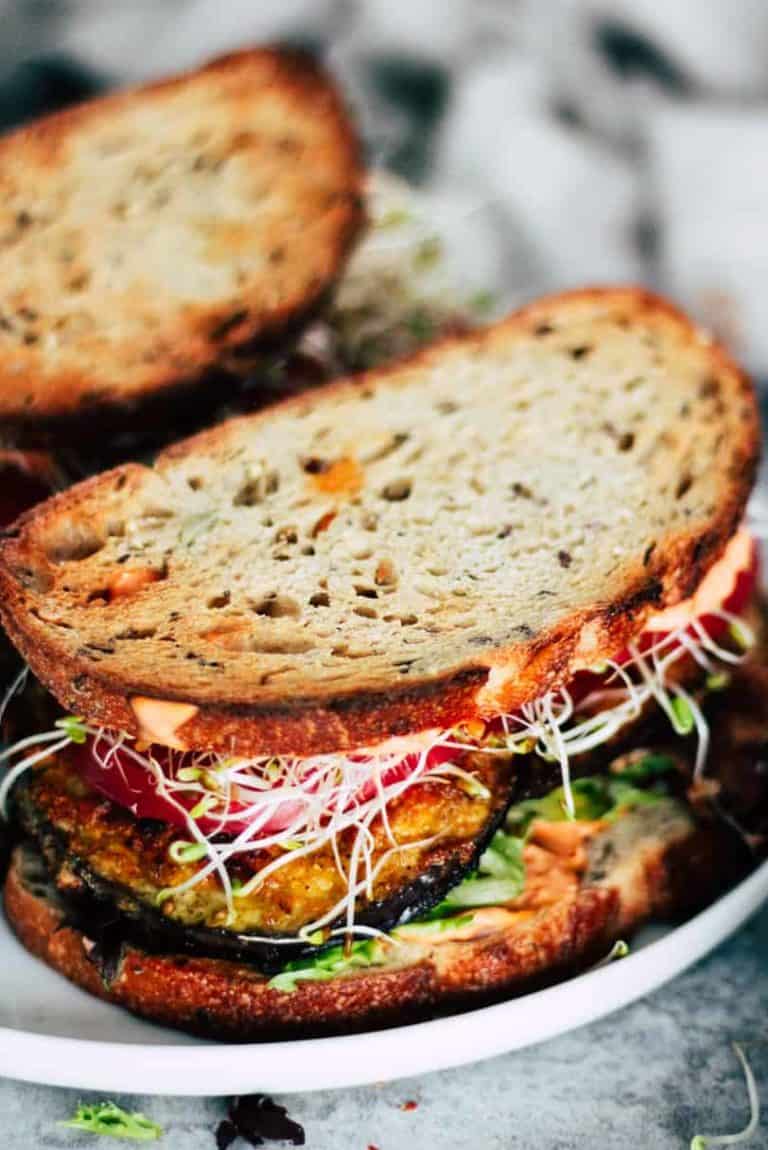 Vegetarian Eggplant BLT on white plate with cream napkin.