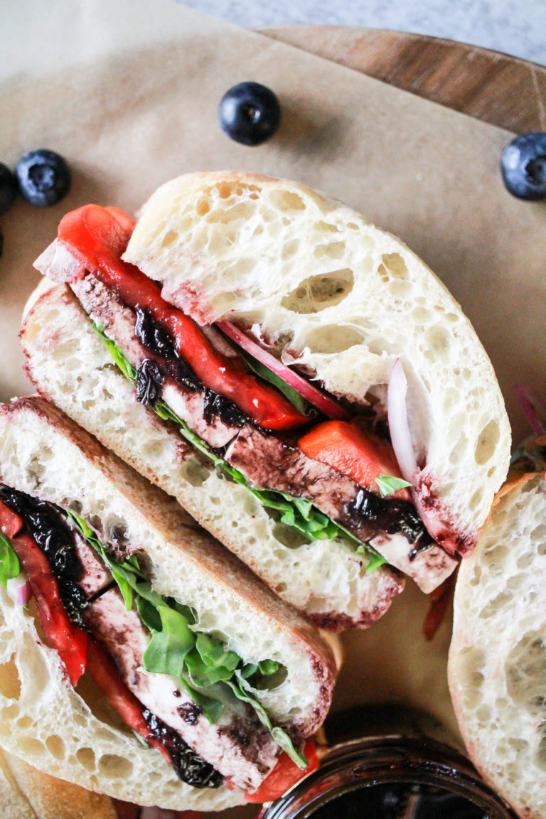 Tomato Mozzarella Sandwich with blueberry sauce and fresh blueberries in the background.