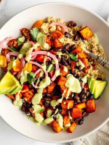 Grain bowl with sweet potato, black beans, quinoa, and avocado dressing.