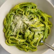 Fettuccine pasta with green spinach sauce and parmesan cheese.