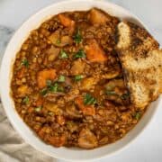 Vegetarian Irish Stew with lentils and mushrooms in a white bowl.