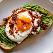 Avocado toast with a sunny-side-up fried egg and chili crunch sauce.