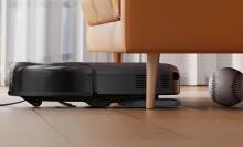 a eufy robot vacuum cleans under the couch with a baseball in front of it