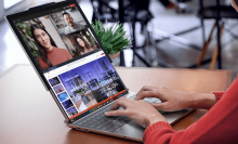 A person types on a laptop. It's screen is extended by a second screen that has been pulled out from the top of the original screen.  