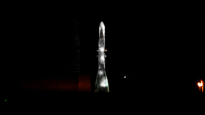 A rocket is seen on a launchpad, illuminated in the dark.