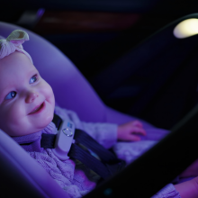 a baby looking at a sensorysoothe handle on an evenflo car seat