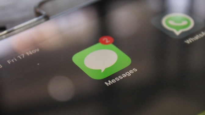 Close up look of iMessage app icon with 2 notifications next to Whatsapp app displayed in tablet screen