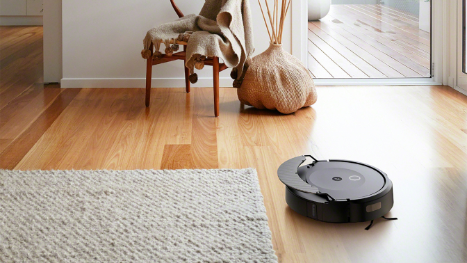 Roomba Combo 10 Max robot vacuum lifting mopping pad while vacuuming hardwood floor with rug and furniture in peripherals