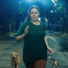 Amy Adams as Mother in "Nightbitch," running at night with dogs.