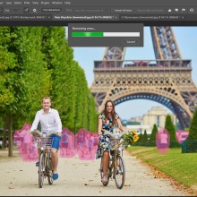 Two people ride bikes in Paris beneath the Eiffel Tower with people behind them highlighted in pink.