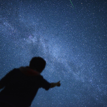 the silhouette of a person gazing at the starry night sky