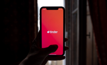 A person holds an iphone screen with the Tinder app open