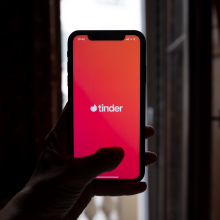 A person holds an iphone screen with the Tinder app open