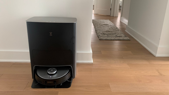 Ecovacs Deebot X1 Omni and station on wooden floor with hallway and rug in background