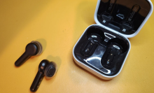 earbuds with stems and their case against a yellow background