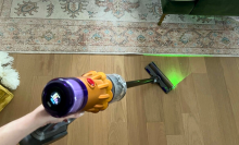 Person holding Dyson V12 Detect Slim to clean hardwood floor with laser on