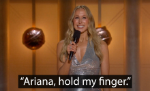 A woman stands on an award show stage. The caption at the bottom reads, "Ariana, hold my finger."