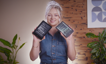 a smiling young woman holding the kindle paperwhite in one hand and the kobo clara colour in the other