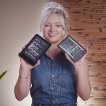 a smiling young woman holding the kindle paperwhite in one hand and the kobo clara colour in the other