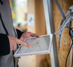 GettyImages - A man in a gray vest is consulting a tablet on a construction site, with visible cables in the background.