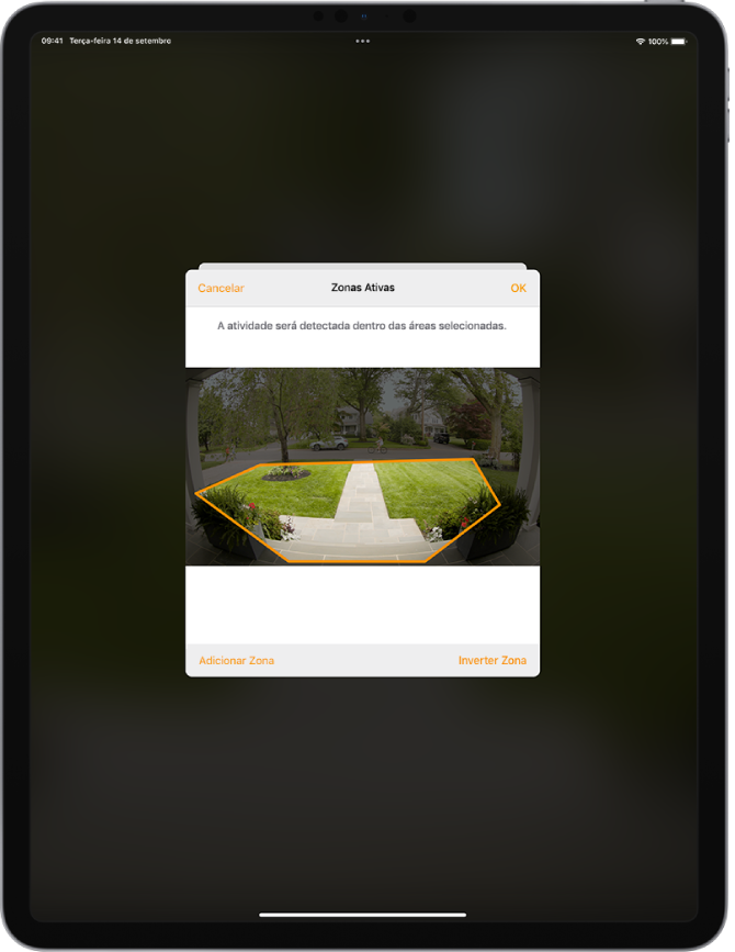 Tela do iPad mostrando uma zona ativa em uma imagem capturada por uma campainha com câmera. A zona ativa abrange a varanda e o caminho da entrada da casa, mas exclui a rua e o acesso da garagem. Os botões Cancelar e OK estão acima da imagem. Os botões Adicionar Zona e Inverter Zona estão abaixo.