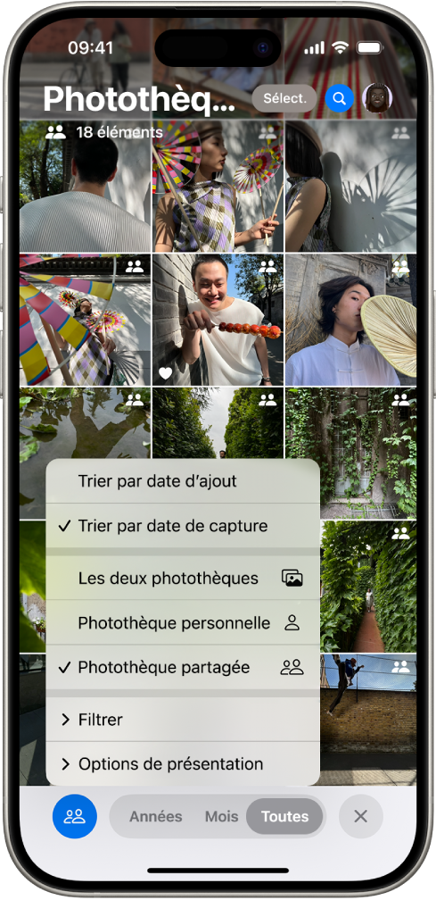 Une photothèque partagée iCloud dans l’app Photos. Le bouton « Photothèque partagée » dans le coin inférieur gauche est sélectionné, et la photothèque partagée est sélectionnée dans une liste d’options de photothèque. Toutes les photos affichées dans la photothèque possèdent une pastille dans le coin supérieur droit indiquant qu’elles appartiennent à une photothèque partagée.