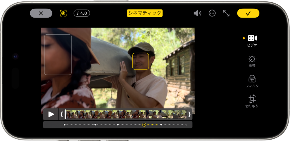 シネマティックモードのビデオの「編集」画面。画面の左上隅には、「キャンセル」ボタン、シネマティック手動ボタンと被写界深度調整ボタンがあります。画面上部の中央では、「シネマティック」ボタンが選択されています。画面の右上には、音量ボタン、その他ボタン、フルスクリーンにするボタン、「完了」ボタンがあります。ビデオが画面の中央にあり、焦点が合っている被写体の周囲にフレームが表示されています。ビデオの下にはフレームビューアがあり、被写体の焦点が変化するビデオ内のポイントが表示されています。画面の右側には、ビデオ、カラーを調整、フィルタ、切り取りの編集ボタンが上下に並んでいます。ビデオ、調整、フィルタ、および切り取り。