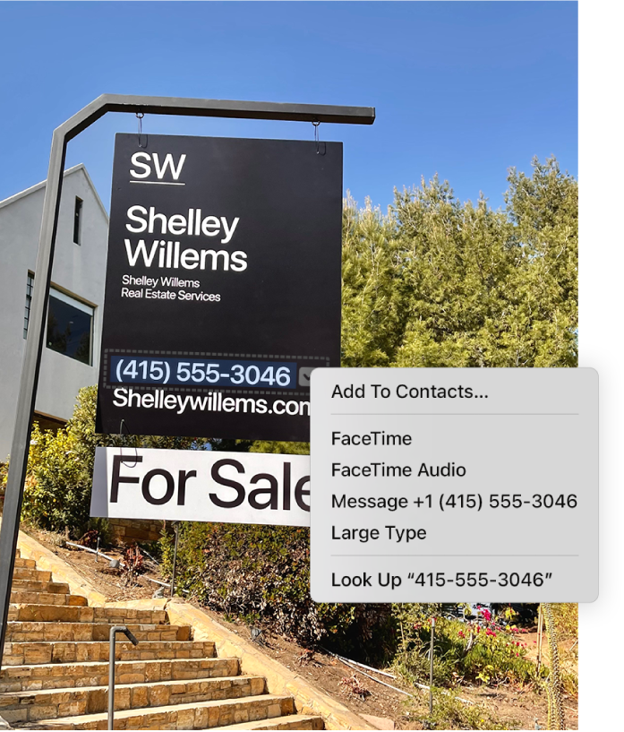 Photo of a Real Estate For Sale sign showing the agent’s phone number selected as Live Text and a menu presenting options to add the phone number to Contacts, call the number, start a FaceTime call, send a text message and more.