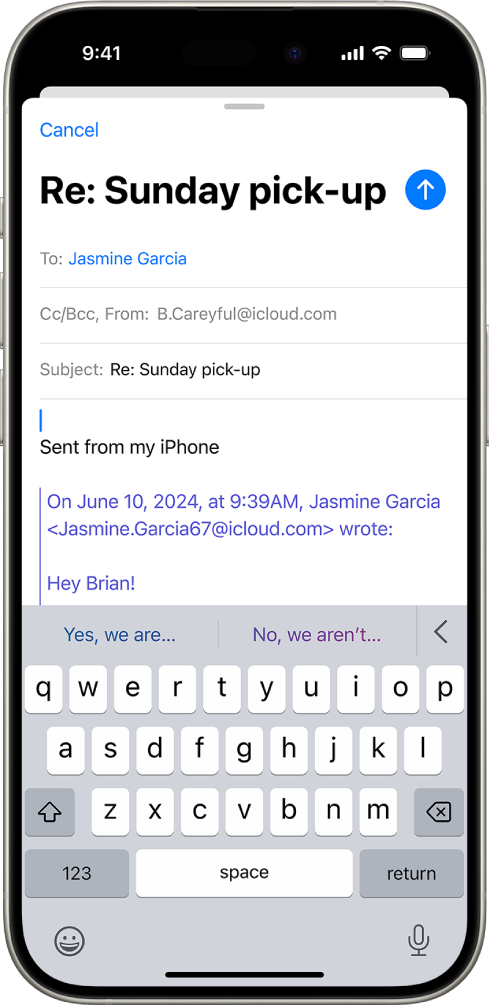 An iPhone showing an email being replied to. Suggested replies appear at the top of the keyboard.