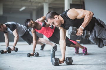 athletes doing pushups with dumbbells on floor