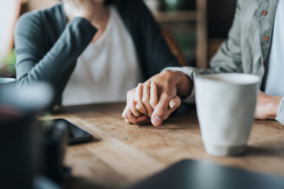 close up of young asian couple on a date in cafe, holding hands on coffee table two cups of coffee and smartphone on wooden table love and care concept