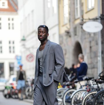 a man on the street wearing a grey suit with adidas samas sneakers in a roundup of the best casual shoes for men 2024