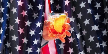 a hand holding a cocktail glass in front of a starpatterned backdrop