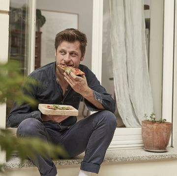 man eating pizza on doorstep