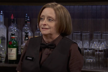 bartender standing in front of a bar with various bottles and glasses