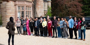 group of people assembled outdoors interacting with a presenter in front of a mansion