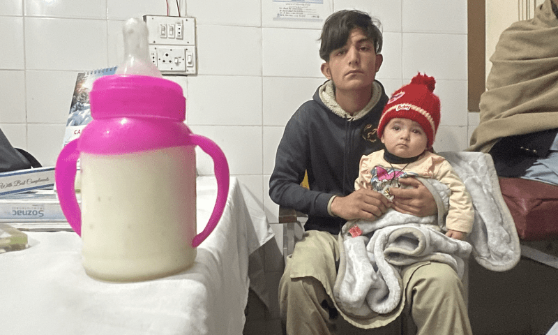 A man sits with an infant at a hospital in Parachinar.