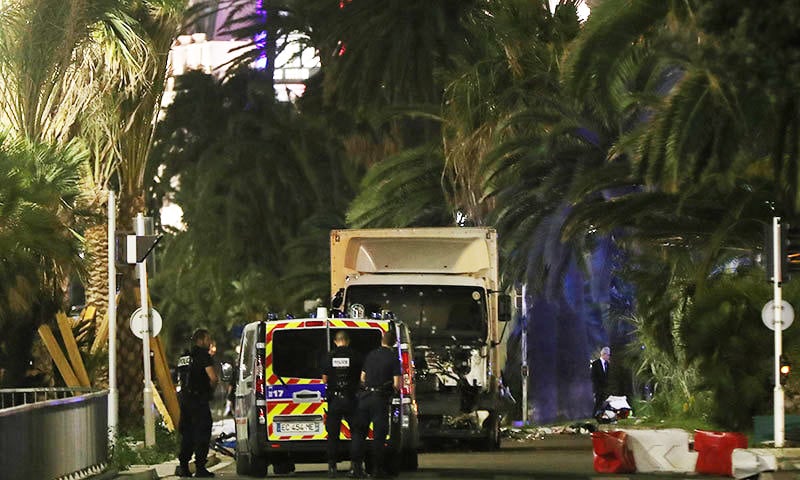 Police officers stand near a van, with its windscreen riddled with bullets, that ploughed into a crowd leaving a fireworks display in the French Riviera town of Nice on July 14, 2016.— AFP