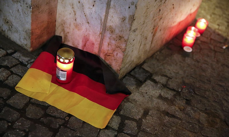 A candle is burning on a German national flag near the attack site.— Reuters