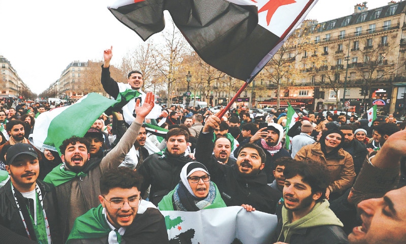 DEMONSTRATORS wave Syrian independence-era flags as they shout slogans during a rally in Paris to celebrate the fall of president Bashar Al Assad.—AFP