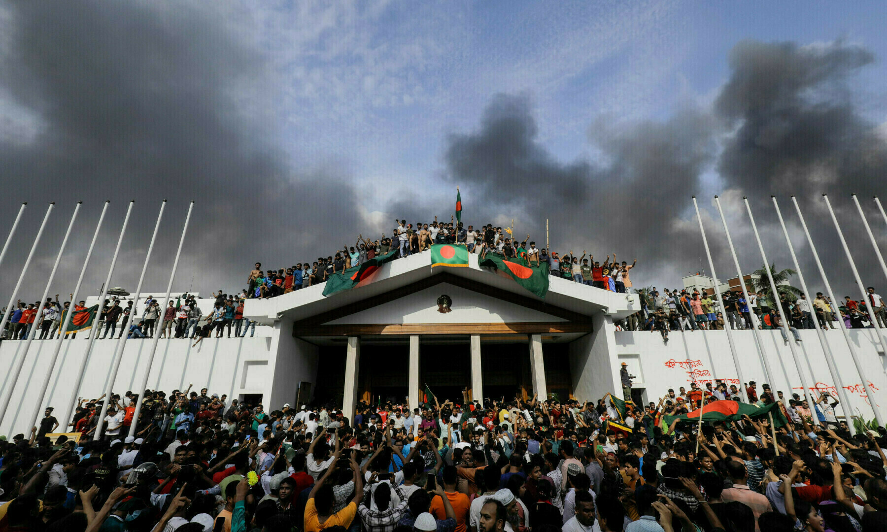 Anti-government protesters display Bangladesh’s national flag as they storm Prime Minister Sheikh Hasina’s palace in Dhaka on August 5, 2024. — AFP