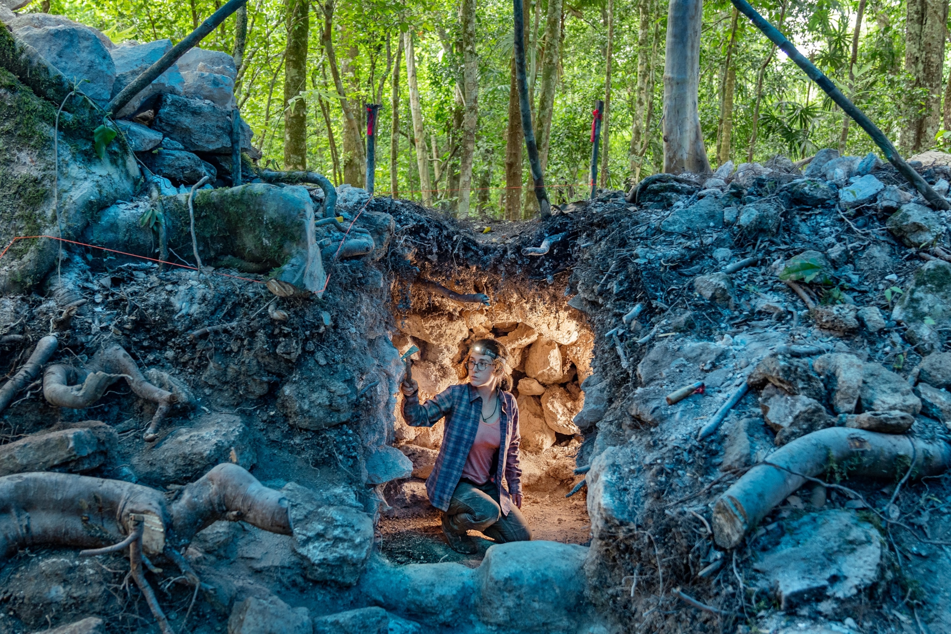 Clara lights up the cave around her as she inspects a burial.