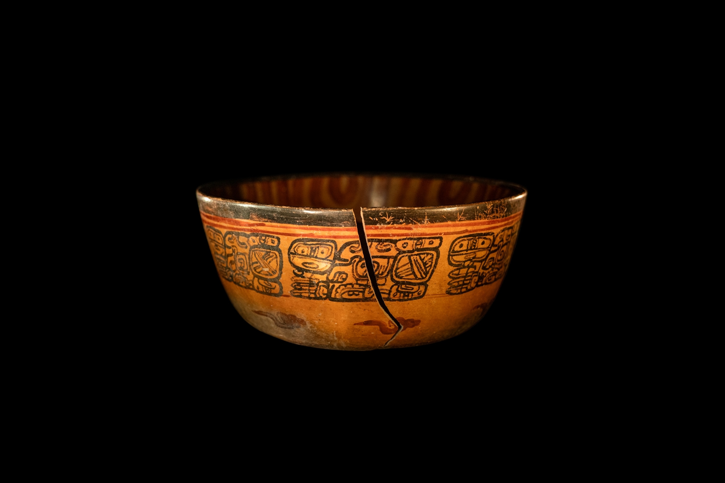 A bowl with a crack down the side has old black scriptures.