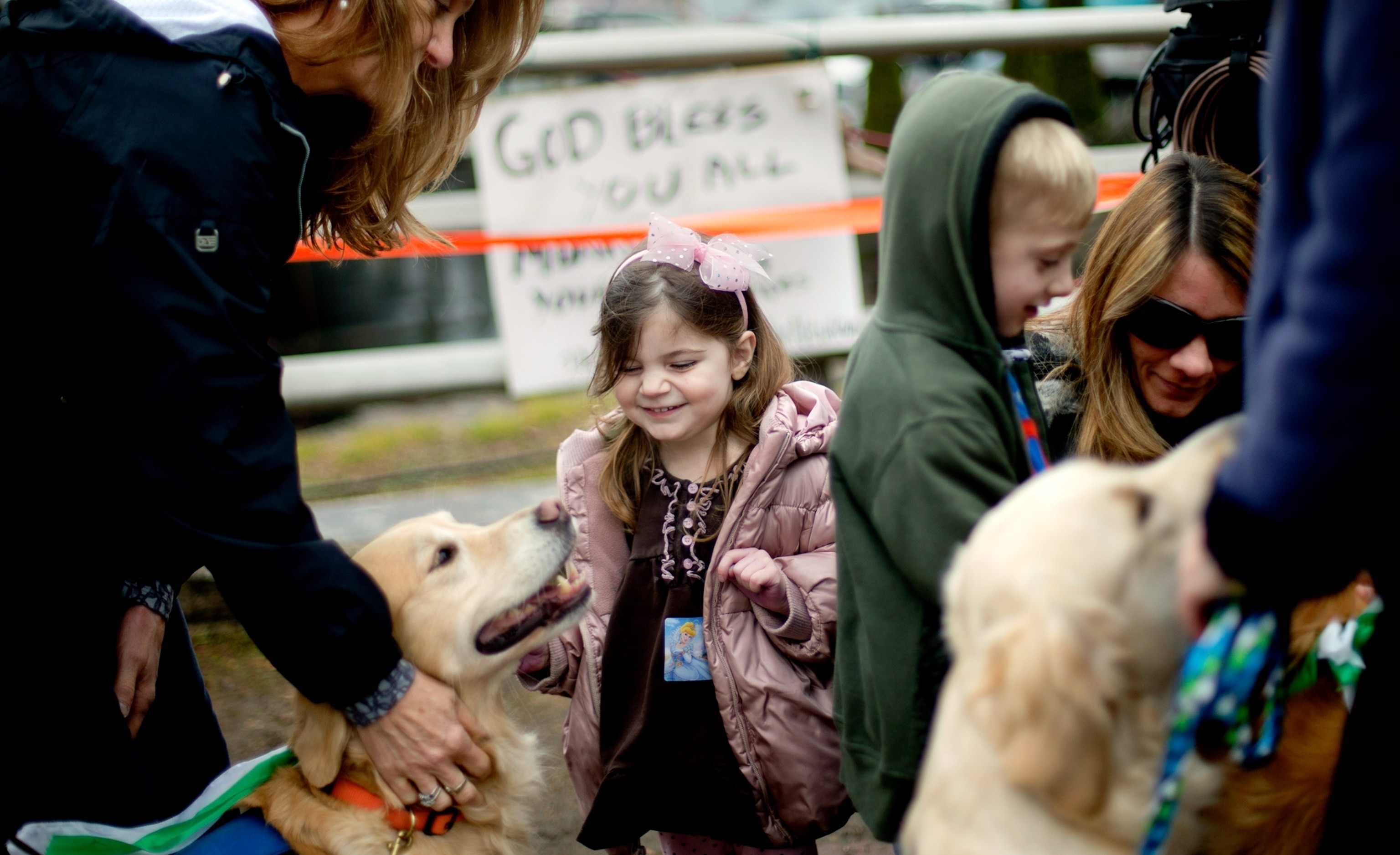 A young child smiles as she pets a therapy dog in Newtown, Connecticut.